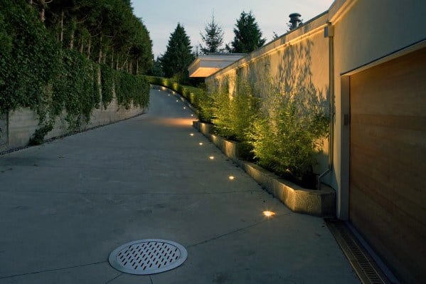 Driveway featuring sleek in-ground lighting along the edges, softly illuminating the path and enhancing the landscaped areas at dus