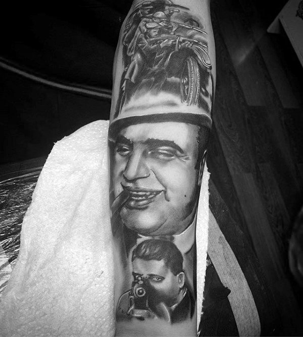 Al Capone tattoo sleeve featuring a smiling portrait of the gangster with a cigar, alongside scenes of a vintage motorcycle and another gangster with a Tommy gun.