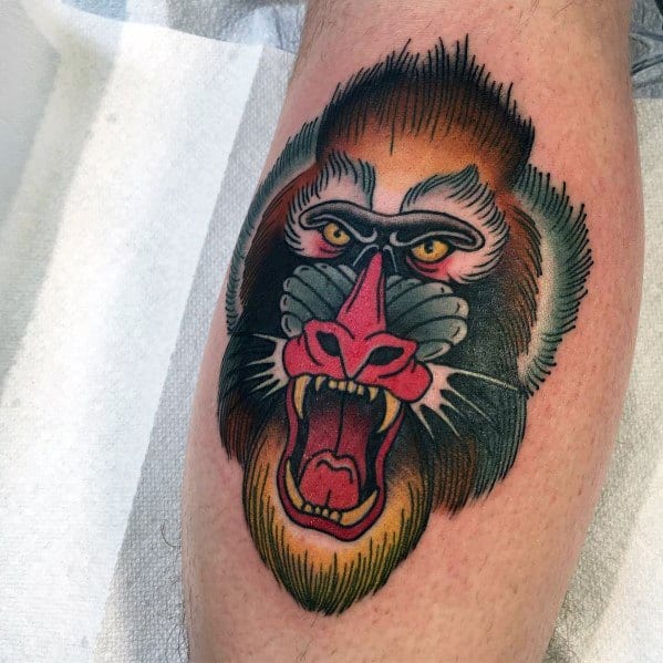 Neo-traditional baboon tattoo with bold outlines, vivid colors, and a fierce expression, featuring dynamic shading for a striking leg design.