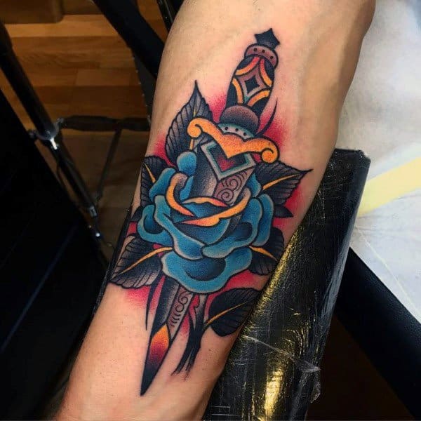 Tattoo of a dagger with a blue rose and black leaves on an arm