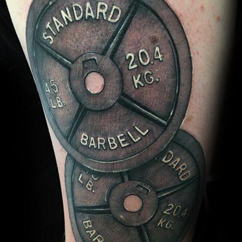 Tattoo of two stacked 45 lb barbell plates with bold lettering, symbolizing strength, discipline, and a passion for heavy lifting.