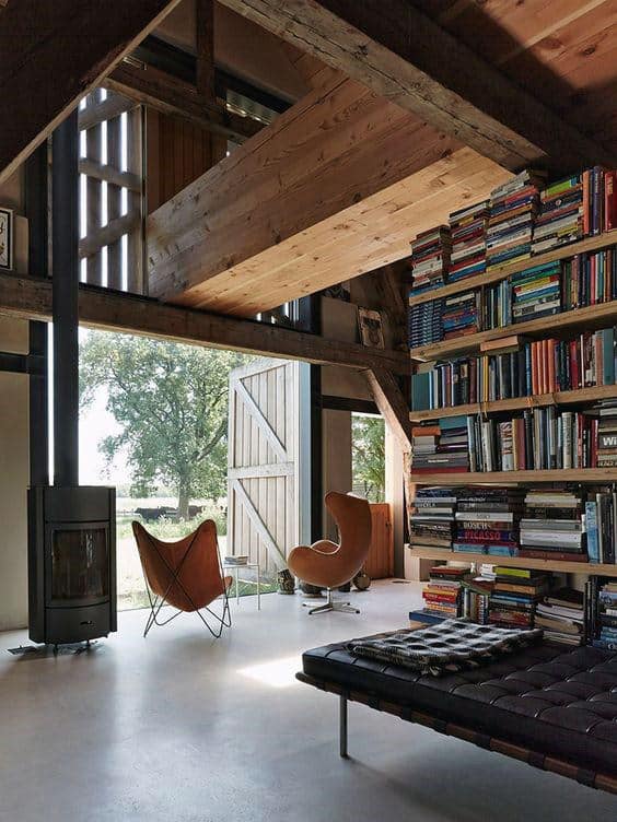 Cozy loft with library shelves, modern chairs, and large windows overlooking greenery