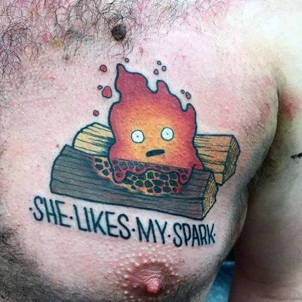 Playful Calcifer chest tattoo with glowing logs, surprised expression, and the bold caption “She Likes My Spark” underneath.