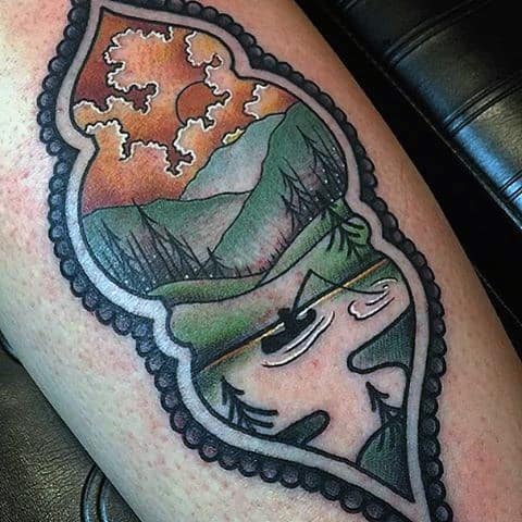 Alt text: Colorful tattoo featuring a canoe on a calm lake with a scenic sunset and mountains, framed in an ornate border for a vintage feel.