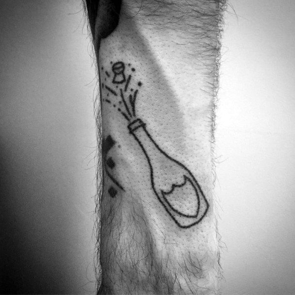 Black and white tattoo of a champagne bottle popping, inked on a person's arm.