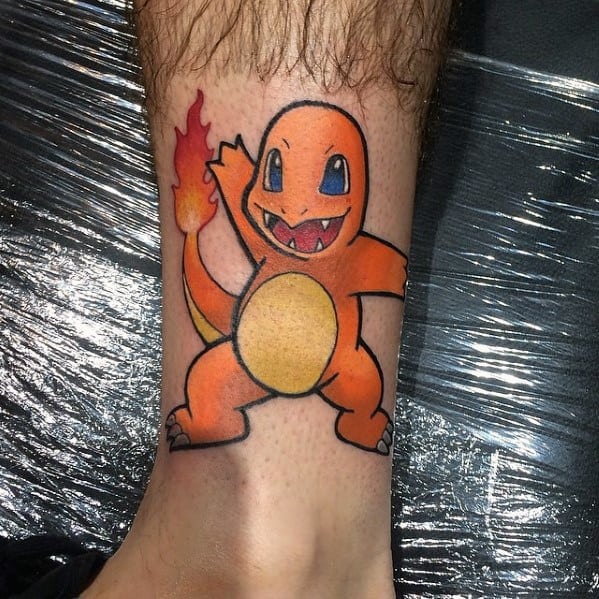 Simple and bold Charmander tattoo on ankle with clean black outlines, open-mouthed smile, and bright flame-tipped tail.