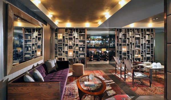 Stylish man cave with plush sofa, modern bookshelves, and warm lighting over a patterned rug and coffee table
