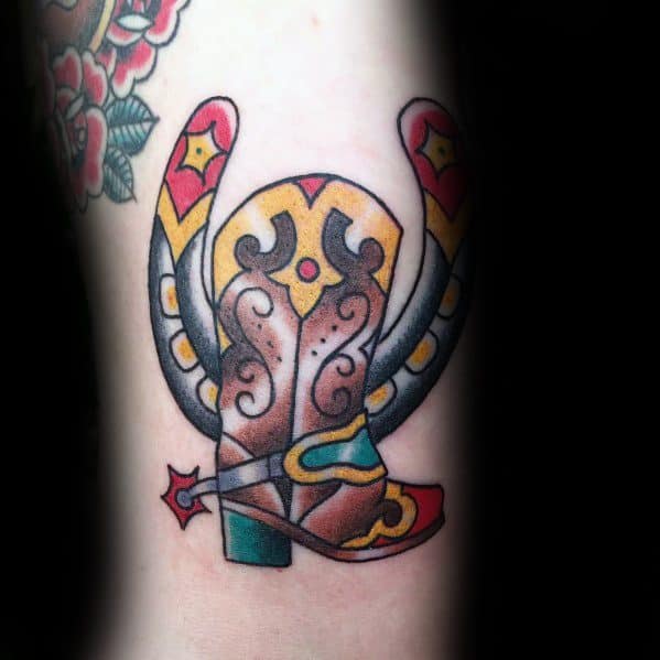 Tattoo of a cowboy boot with a horseshoe, spur, and bold Western-style patterns, symbolizing luck, resilience, and cowboy spirit.