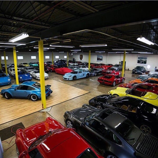 A vast garage with yellow pillars and a vibrant collection of classic and modern sports cars.