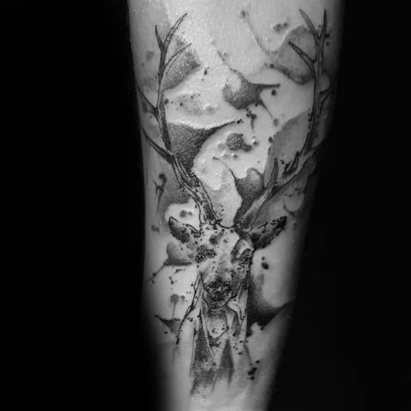 Abstract black and grey elk tattoo on the forearm, featuring watercolor-style splashes and fine shading for a bold and artistic design.