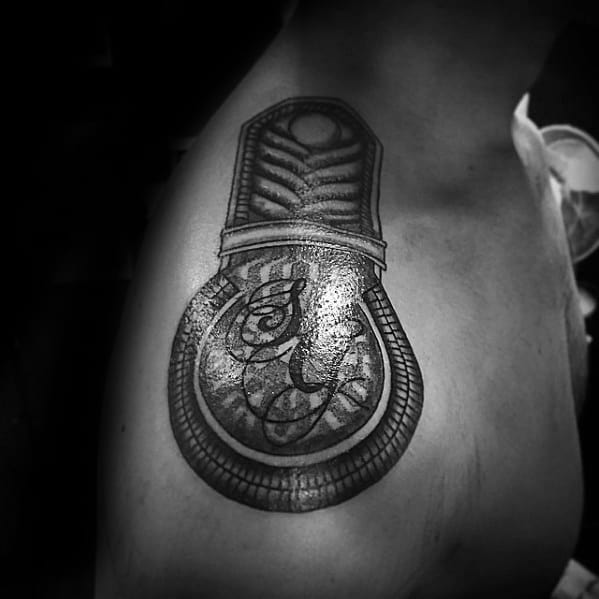 Dark epaulette tattoo featuring bold shading, a central script-style letter, and a thick braided border on the upper arm.