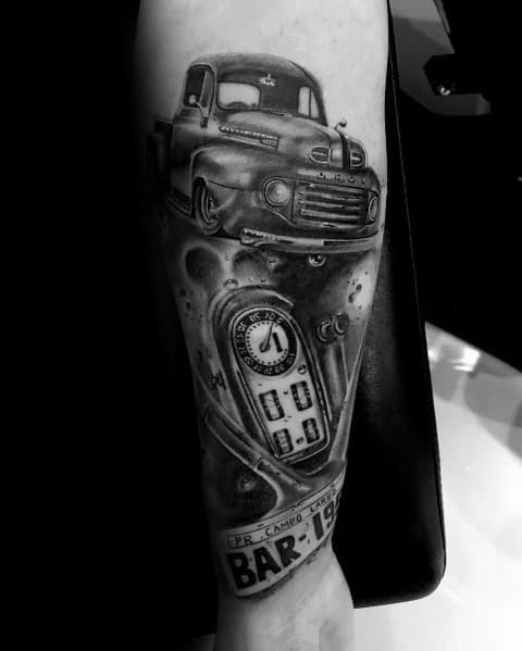 Realistic black and grey Ford vintage truck tattoo on forearm, featuring detailed shading, a gas pump, and nostalgic automotive elements.