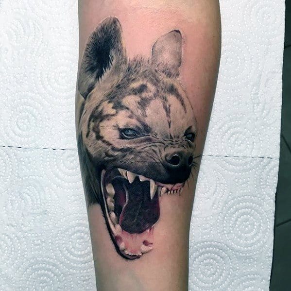 Detailed hyena tattoo on the forearm, showing an aggressive snarl with exposed teeth and intense blue eyes for a lifelike effect.