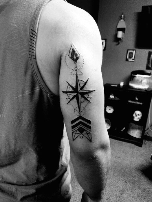 Geometric compass tattoo on tricep with arrowhead, chevrons, and dotted accents, blending navigation and tribal-style elements.