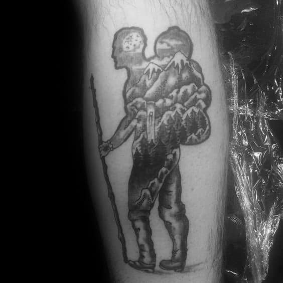 This tattoo blends the silhouette of a hiker with a mountain landscape, symbolizing a deep connection to nature and the spirit of adventure.