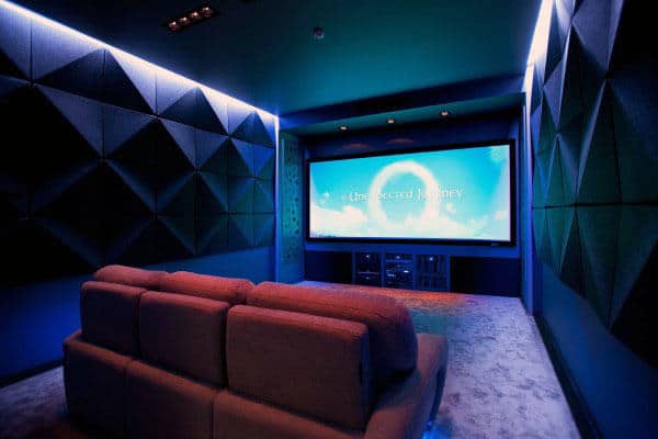 Blue-lit home theater with a large screen and a cozy sofa facing the screen