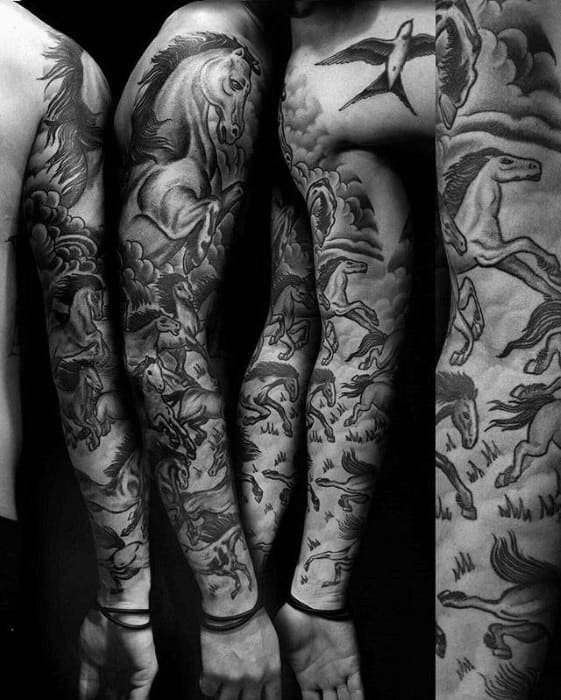 Full sleeve black and grey tattoo of galloping horses in dynamic motion, with clouds and a flying bird on the upper arm
