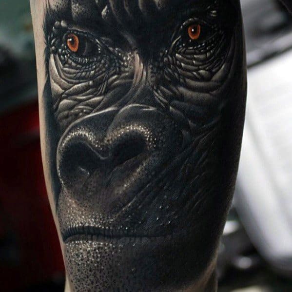Ultra-realistic King Kong tattoo featuring a close-up of his face with detailed skin texture and striking amber eyes.