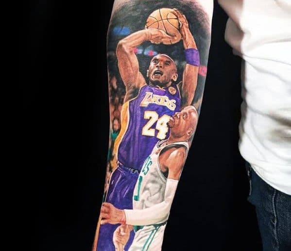 A colorful tattoo of Kobe Bryant taking a shot in his Lakers jersey, with number 24, over an intense game moment against a Celtics player.