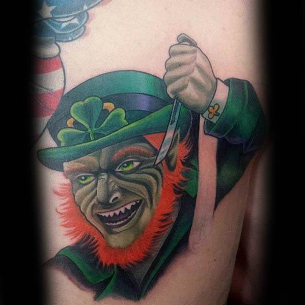 Sinister leprechaun tattoo with glowing green eyes, fiery orange beard, and a wide grin, holding a knife while wearing a clover hat and green coat.