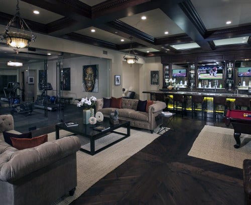 Luxurious home bar and lounge with plush seating, pool table, and exercise area, featuring elegant lighting