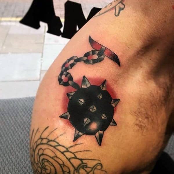 Bold black and red mace tattoo featuring a spiked ball on a chain, creating a striking contrast and symbolizing strength and power.