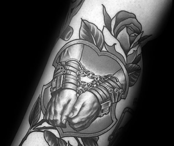 Black and grey tattoo of chained hands breaking free, surrounded by roses