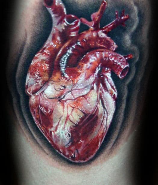 Realistic tattoo of an anatomical human heart in vivid red and pink hues with detailed veins and arteries