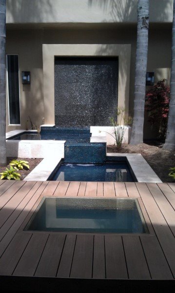 Modern backyard water feature with a black tiled wall fountain and sleek geometric pool design.