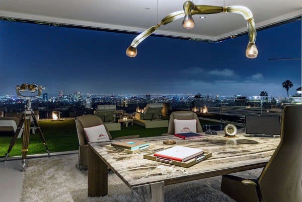 Luxurious home office with rustic desk, city night view, and outdoor seating area.