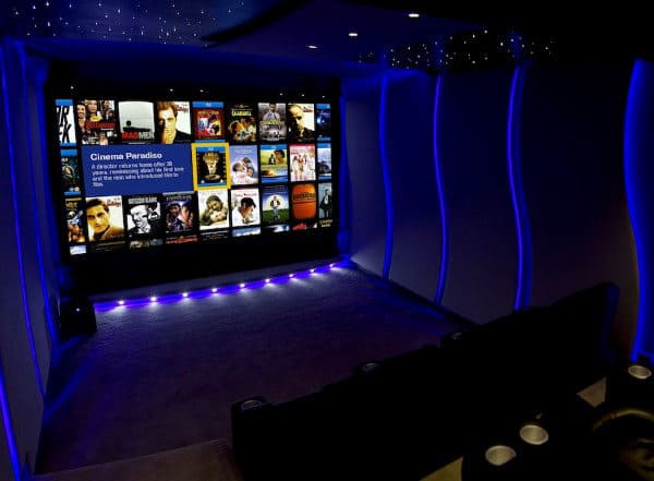 Home theater with a large screen showcasing movie options and bathed in soothing blue ambient lighting