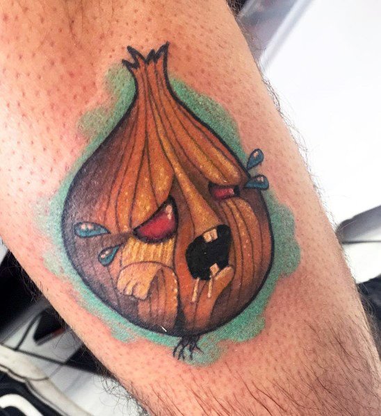 Colorful cartoon-style tattoo of an anthropomorphic onion with red eyes, fangs, and tears, featuring bold outlines and a vibrant green glow.