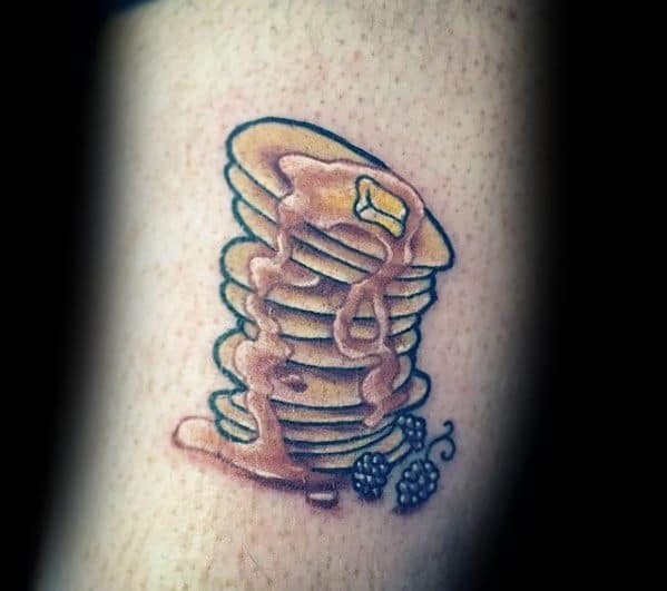 Tall stack of pancakes tattoo with dripping syrup, butter, and blackberries, featuring soft shading for a realistic and appetizing look.