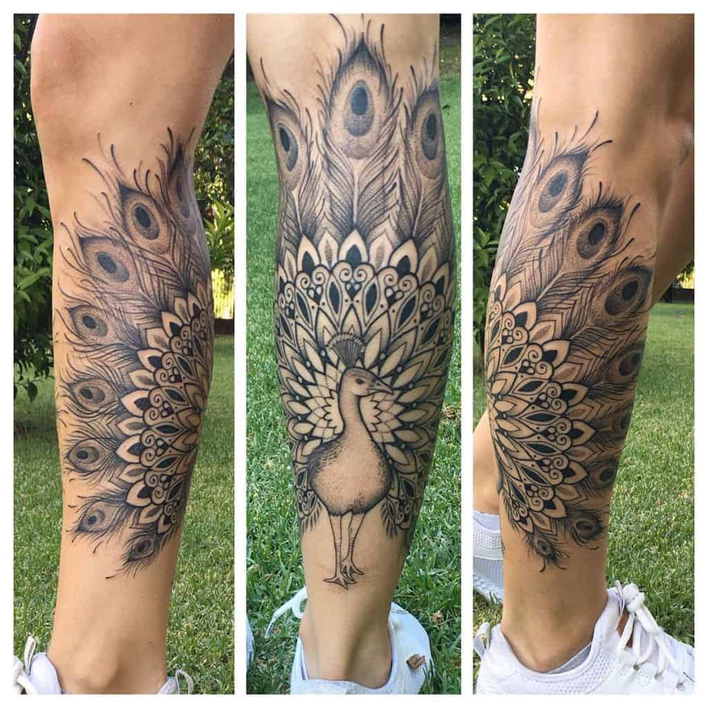 Intricate black and white peacock tattoo wrapping around the leg, featuring detailed feathers and a central bird design.