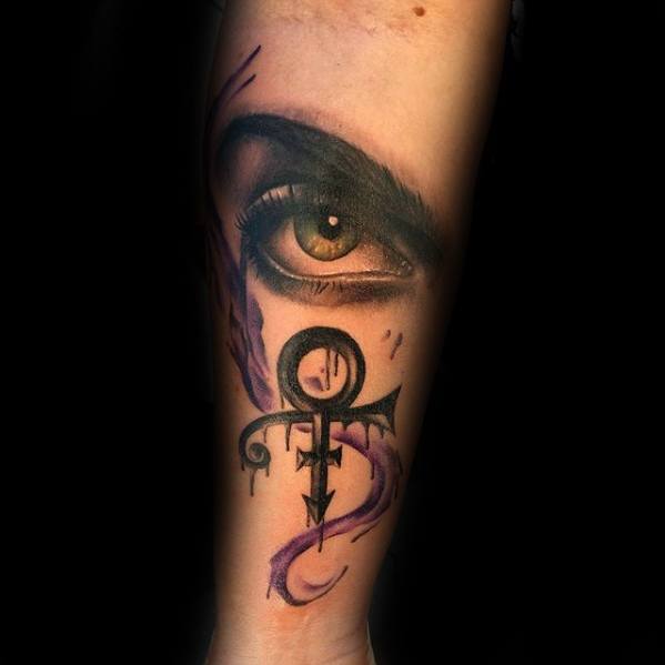 A striking tattoo featuring an intense eye, Prince's iconic symbol, and purple accents symbolizing his legacy