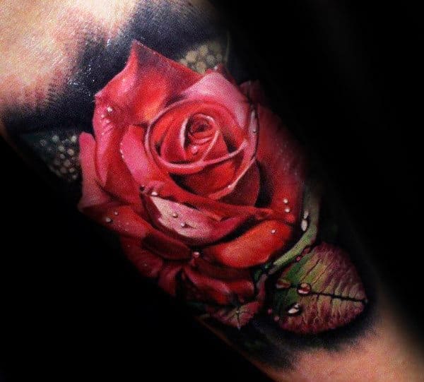 A detailed tattoo of a red rose with dewdrops on petals and leaves