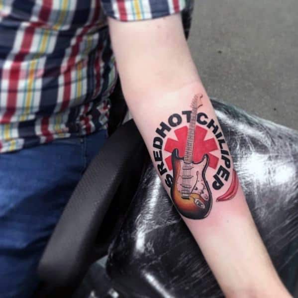 Forearm tattoo featuring the Red Hot Chili Peppers logo with a detailed electric guitar design and bold lettering around the emblem.