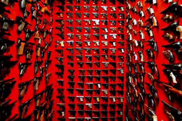 Striking gun room with vibrant red walls showcasing an extensive pistol collection.
