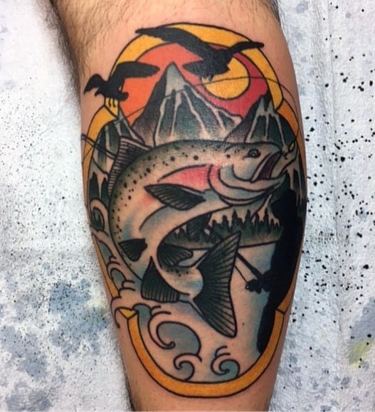Bold traditional-style tattoo of a leaping salmon framed by mountains, birds, and waves, featuring vibrant colors and strong black outlines.