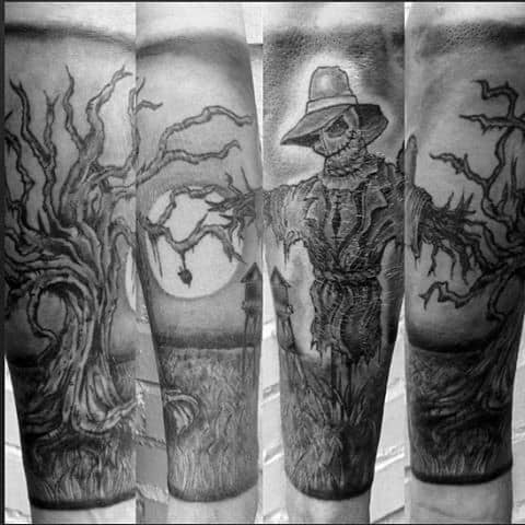 Forearm sleeve tattoo with a creepy scarecrow, full moon, haunted trees, and distant farmhouse in detailed black and grey ink.