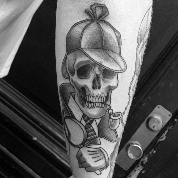 Tattoo of a skull with a detective hat, pipe, and magnifying glass inspired by Sherlock Holmes