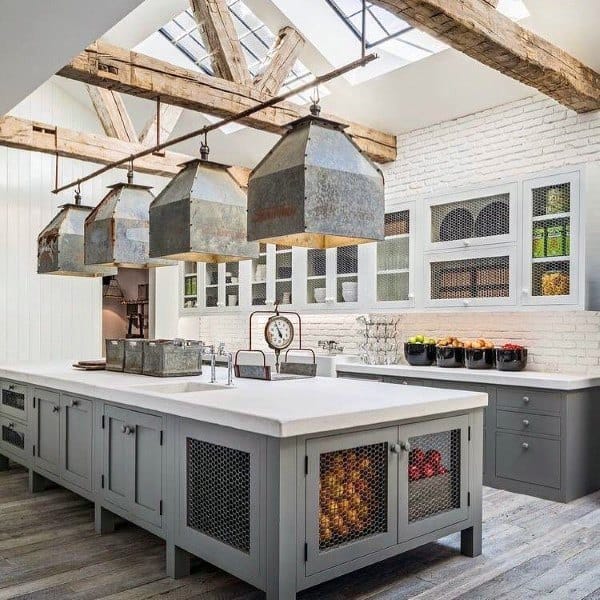 Rustic kitchen with skylight, exposed beams, gray cabinets, metal pendant lights, and white brick walls.