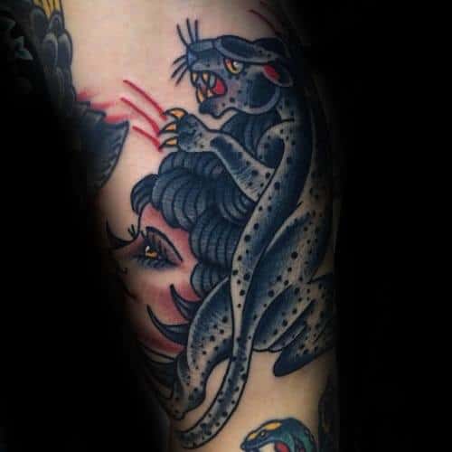 Neo-traditional snow leopard tattoo in dark tones, showing the cat clawing through a woman's hair with bold outlines and red accents.