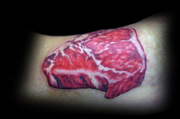 Tattoo of a highly detailed and realistic raw steak with rich marbling, bold shading, and depth, creating a lifelike meat-inspired design