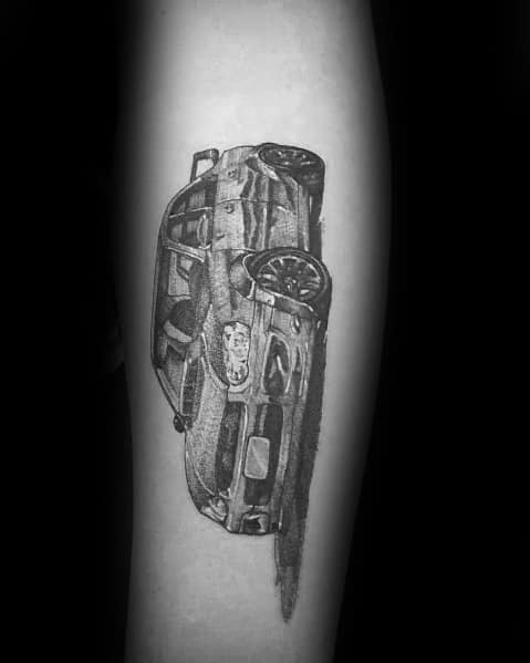 Detailed black and grey Subaru rally car tattoo on the forearm, showcasing a dynamic perspective with realistic shading and motion effects.
