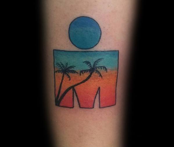 Ironman logo tattoo with a tropical sunset scene inside, featuring a gradient of orange, teal, and blue with palm trees.