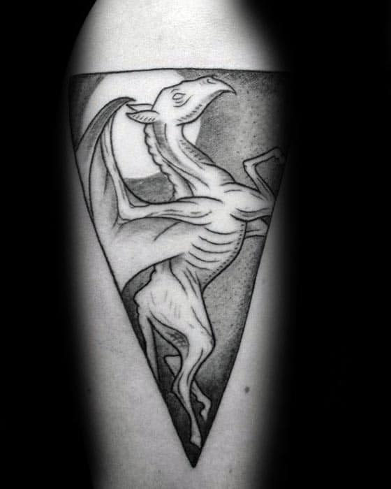 Minimalist Thestral tattoo inside a triangle frame, featuring clean lines and dotwork shading with a full moon in the background.