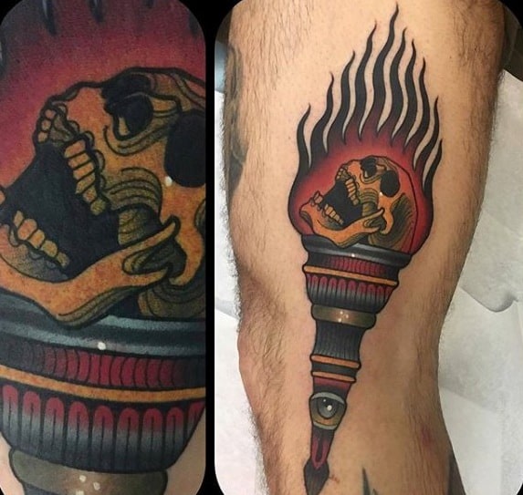 Torch tattoo with a fiery skull inside the flame, deep red and gold tones, and an eye detail on the base for a surreal effect.