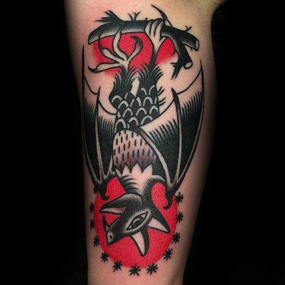Traditional bat tattoo hanging upside down over a red moon, with bold black shading and stars surrounding the head.