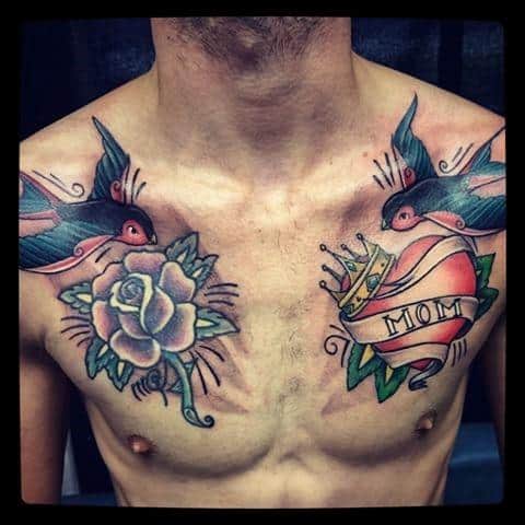 Traditional chest tattoo with two swallows, a white rose on one side, and a crowned red heart with a "MOM" banner on the other.